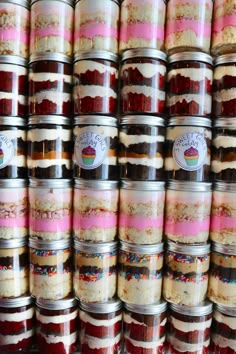 many jars filled with different types of desserts on top of each other in front of a wall