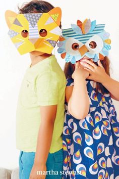 two young children wearing paper masks on their faces, one is holding the other's face