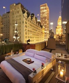 a bed sitting on top of a wooden platform next to tall buildings in the city