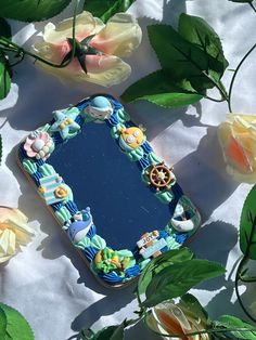 a mirror sitting on top of a table surrounded by flowers and leaves with roses around it