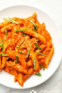 a white plate topped with pasta covered in sauce and garnished with parsley