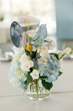 a vase filled with blue and white flowers sitting on top of a table next to a cake