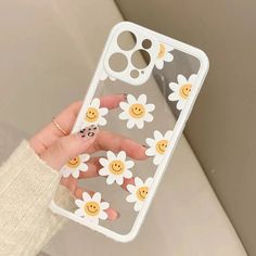 a woman's hand holding an iphone case with smiley faces and daisies on it