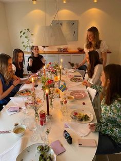 a group of women sitting around a table with plates of food and drinks in front of them