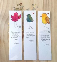 two bookmarks with birds on them sitting on a table next to some confetti