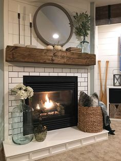 a fire place in a living room next to a basket with flowers and candles on it