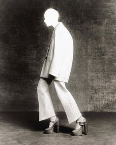 a black and white photo of a man in a suit with his foot on the ground