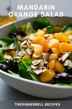 mandarin orange salad with almonds and spinach in a white bowl on a table