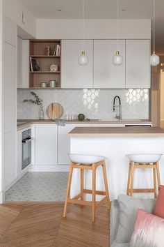 a kitchen with two stools in front of an island