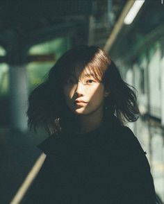 a woman standing in front of a train station with her hair blowing in the wind