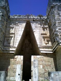 the entrance to an ancient building with stone pillars and doorways on either side, against a blue sky