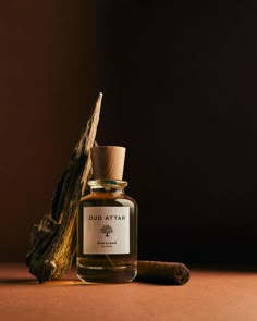 an open bottle of oud atta sitting next to a small stick of wood