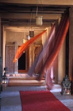 a red rug is in the middle of a room with an open door and hanging lanterns