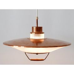 a light fixture hanging from the ceiling with a white wall behind it and a brown shade on top