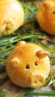 small pigs made out of bread sitting on top of some green grass with leaves around them