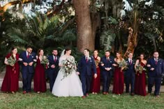 a bride and groom with their bridal party in front of a palm tree at sunset