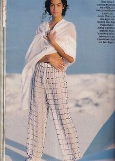 a woman in white shirt and pants standing on snow covered ground