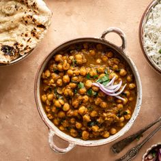 two bowls filled with chickpeas and rice next to some pita bread on a table