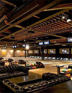 an indoor bowling alley with couches and tables