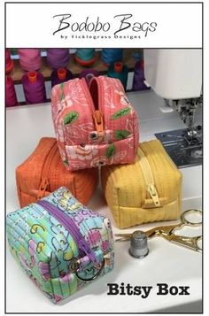 three purses sitting next to each other on top of a sewing machine with scissors