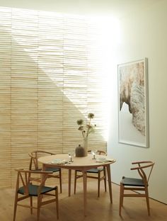 a dining table and chairs in front of a wall with bamboo slats on it