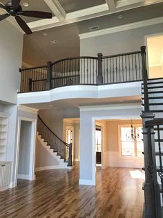 an empty living room with wood floors and a ceiling fan in the middle of it