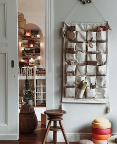 a white wall hanging on the side of a room next to a stool and table