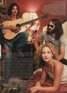 a woman sitting on top of a bed next to a man holding an acoustic guitar