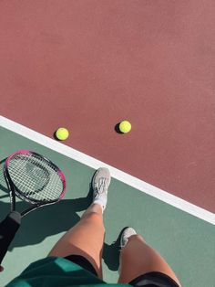 a person standing on a tennis court holding a racquet and two tennis balls