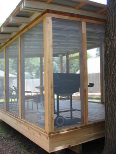 a covered patio area with grill and table in the back ground next to a tree