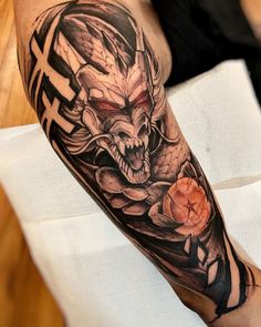 a man with a tattoo on his arm is holding a rose and an evil demon