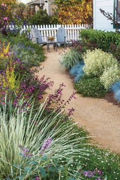 a white picket fence sitting next to a garden filled with lots of flowers and plants