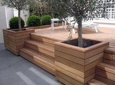 there is a tree that is in the middle of this wooden planter box on the deck