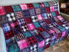 a couch covered in a multicolored patchwork blanket sitting on top of a rug