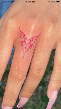 a woman's hand with a small tattoo on her left thumb and pink nail polish