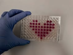 a gloved hand is holding a heart - shaped contraption in front of a white background