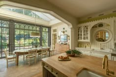 a kitchen with lots of windows and wooden counter tops in front of an oven, sink and dining room table