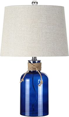 a blue glass table lamp with a roped cord on the base and a beige linen shade