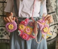 a woman holding two crocheted purses in her hands