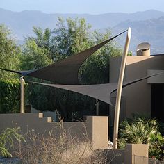 an outdoor patio area with shade sails and mountains in the background