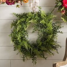 a wreath is hanging on the wall next to a chair