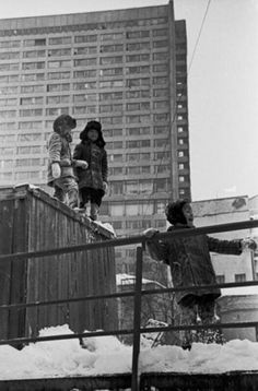 black and white photograph of children playing in the snow on top of a boxcar