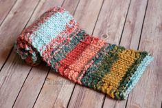 a multicolored knitted tie laying on top of a wooden floor