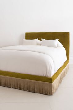 a large bed with white sheets and pillows on it's headboard in a room