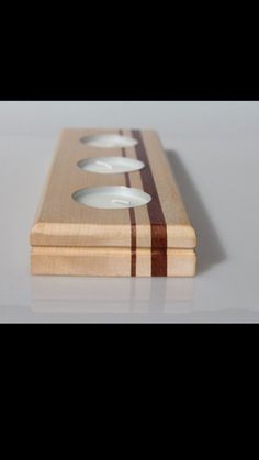 three candles sitting on top of a wooden box with stripes around the candle holders,