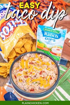 an easy taco dip recipe in a bowl next to chips and other snacks on a table