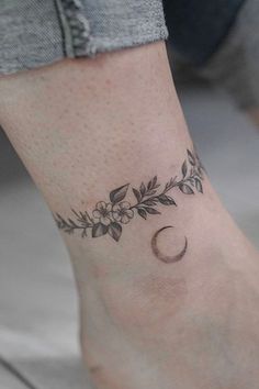 a woman's foot with a flower and crescent tattoo on her left side ankle