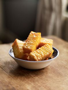 sliced pieces of pineapple sit in a bowl on a wooden table top, ready to be eaten