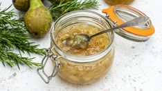 a jar filled with honey sitting on top of a counter next to some pears