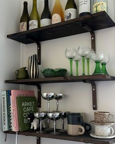 two shelves with wine glasses, cups and books on them